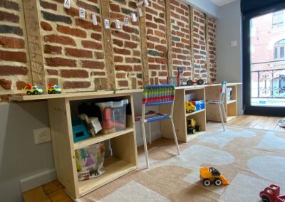 Aménagement salle de jeux enfants. Meubles sur mesure, rangements, petites chaise, murs en briques apparentes. Aménagement décoration intérieur Douai