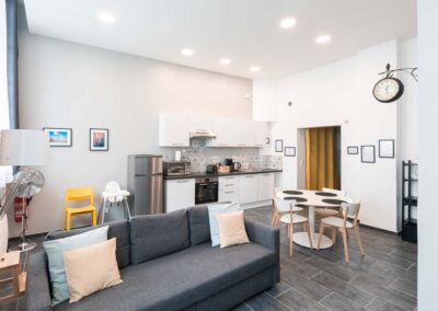 Pièce de vie appartement location type Airbnb. Murs blancs, touches de jaune et de gris. Meublé de tourisme / gîte / Airbnb. Aménagement décoration intérieur Douai